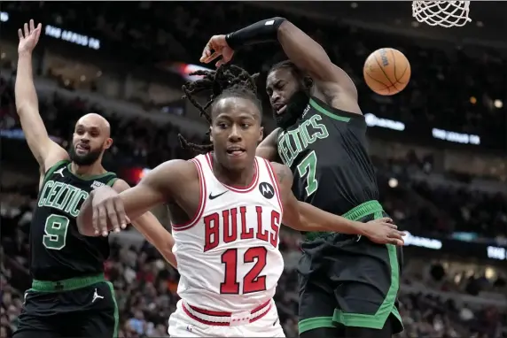  ?? CHARLES REX ARBOGAST — THE ASSOCIATED PRESS ?? Chicago Bulls’ Ayo Dosunmu (12) braces for a fall after Boston Celtics’ Jaylen Brown (7) blocked his shot as Celtics’ Derrick White defends during the second half of an NBA basketball game Thursday, Feb. 22, 2024, in Chicago.