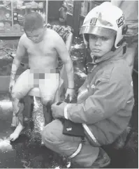  ?? — Gambar Bernama ?? LECUR: Seorang anggota bomba dan penyelamat memberi bantuan kepada Teoh Hwa Teik, 12, yang melecur sebanyak 20 peratus dibadan dan kaki.