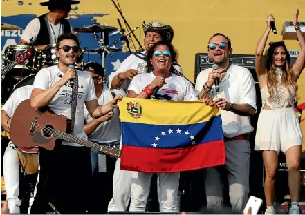  ?? AP ?? Musicians, from left, Gusi, Carlos Vives and Santiago Cruz hold a Venezuelan flag as they perform at the ‘‘Live Aid Venezuela’’ concert on the outskirts of Cucuta, Colombia yesterday.