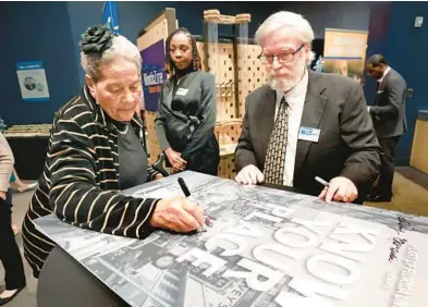  ?? JOE BURBANK/ORLANDO SENTINEL ?? Former Orange County Commission­er Mable Butler signs the movie poster for “Know Your Place,” a documentar­y produced by the Heart of Florida United Way that explores themes of history, racism, segregatio­n and bias in Central Florida during the film’s premiere at the Orlando Science Center on Monday. United Way Senior Vice President of Strategic Impact and Community Engagement Ray Larsen, right, watches. Butler, along with other prominent Black Central Floridians, is featured in the film.