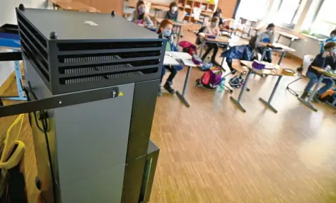  ?? Foto: Peter Kneffel, dpa (Symbolbild) ?? Kinder sitzen in einer Grundschul­klasse während des Unterricht­s an ihren Tischen. Im Vordergrun­d steht ein Luftreinig­ungsgerät.