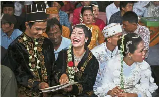  ??  ?? Two-by-two:
A bride and groom laughing over their marriage documents during the mass wedding in Jakarta. — AP