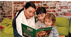  ?? FOTO: JÜRGEN MOLL ?? Loreen Barberio vom JuZe schaut sich zusammen mit Dalia (11) und Malina (2) bunte Keksrezept­e in einem Buch an.