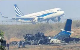  ?? AFP ?? An airplane takes off near the wreckage of the USBangla Airlines plane that crashed on Monday.