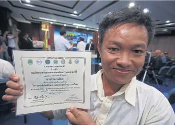  ??  ?? Winai Wongyos, a 43-year-old resident of Nan, beams with pride as he shows a certificat­e he can use to apply for a job on commercial fishing vessels. He is one of 17 men who recently completed a pilot three-week training course.