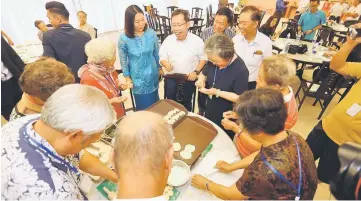  ??  ?? Dr Sim (centre), with Ruan on his right, mingling with the elderly visitors who are seen making Chinese dumpling (jiaozi) at the dining area. — Photos by Muhd Rais Sanusi.