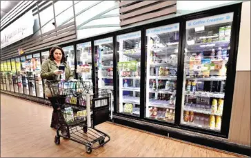  ?? AFP ?? Instacart employee Monica Ortega checks her cellphone for orders while picking up groceries from a supermarke­t.