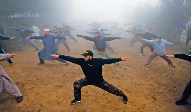  ?? Associated Press ?? ↑ People go through a yoga session in a fog-covered Lahore park on Wednesday.