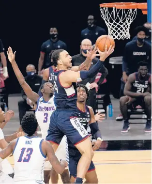  ?? CHARLES REX ARBOGAST/AP ?? UConn’s Tyrese Martin drives to the basket between DePaul’s Kobe Elvis (3) and Darious Hall on Monday in Chicago. Martin led the Huskies with 18 points.