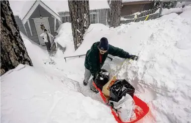  ?? Jae C. Hong/Associated Press ?? Angie Gourirand walks down the snow-covered steps of her home with groceries on a sled Tuesday in Running Springs, Calif., before a new winter storm moved into the already beleaguere­d state.