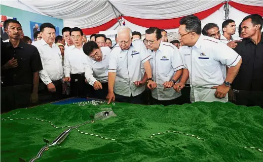  ??  ?? Najib and Chinese State Councillor Wang Yong (fourth from left) looking at a replica of the ECRL after the ground-breaking ceremony in Kuantan. Looking on are Transport Minister Liow Tiong Lai (third from right) and Terengganu Mentri Besar Datuk Seri...