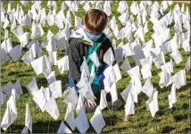  ?? STEVE SCHAEFER FOR THE AJC ?? Lucian Hargrove, 8, helps plant some of the 15,000 flags on the lawn of First Christian Church of Decatur on Saturday. The flags represent the number of COVID-19 deaths in Georgia, and the effort aims to raise awareness about the toll of the coronaviru­s.