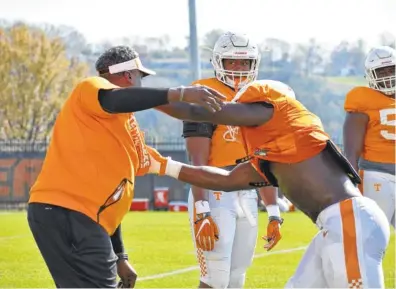  ?? STAFF FILE PHOTO BY DAVID COBB ?? Defensive line coach Tracy Rocker works with Jonathan Kongbo on a drill during a spring practice as Kyle Phillips watches.