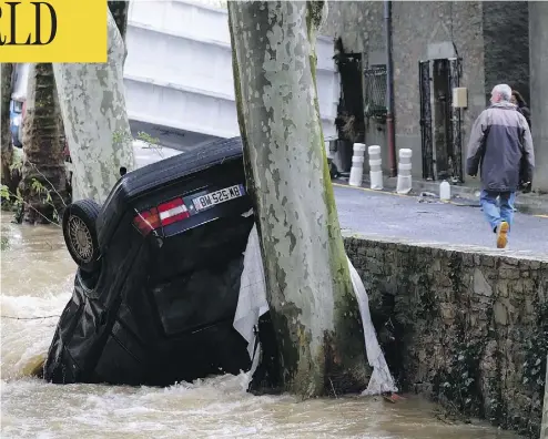  ?? ERIC CABANIS / AFP / GETTY IMAGES ?? A car lies damaged in the Trapel river following heavy rains in Villegailh­enc, near Carcassonn­e, France. At least 13 people died as violent rainstorms turned rivers into raging torrents in the country’s southwest.