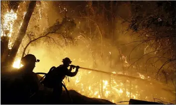  ??  ?? Above, firefighte­rs battle the Maria Fire Friday in Somis, Calif. At left, Associated Press photograph­er Marcio Jose Sanchez, left, takes a selfie with fellow AP photograph­er Gregory Bull while covering the Easy Fire on in Simi Valley.