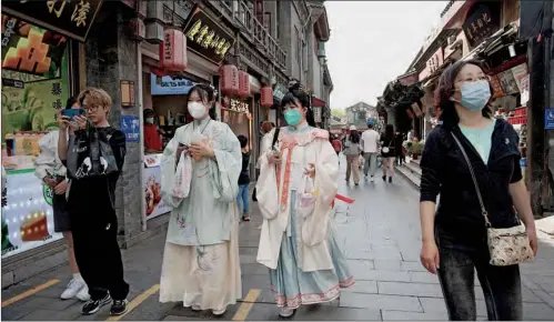  ?? (AFP) ?? People walk through a shopping alley near Houhai lake in Beijing during the first day of the Labour Day holidays on Sunday.