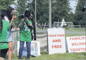  ??  ?? Immigrants watch the “Free Our Families” peaceful vigil Friday, July 17, behind a fence as protesters call for freedom of the children and parents housed in the Berks Residentia­l Center in Bern Township.