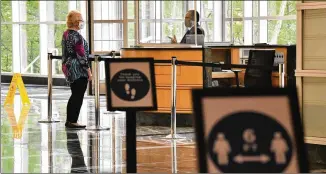  ??  ?? Plexiglass dividers are set up at reception Wednesday in the lobby of the One Overton Park building in Cobb County where Gas South headquarte­rs is located. Workers are allowed to come in on a rotating schedule, with no more than about 12% of the staff in at any time.