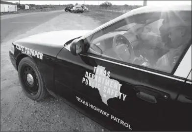  ?? Associated Press ?? TEXAS: A Texas State Trooper is shown sitting in his vehicle in Eldorado, Texas. Drivers in Texas busted for drunken driving, not paying child support or low-level drug offenses are among thousands of "high-threat" criminal arrests that officials have...