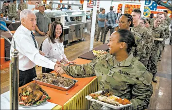  ?? ANDREW HARNIK/AP ?? Vice President Mike Pence, left, and his wife, Karen Pence, second from right, serve turkey for the Thanksgivi­ng holiday to troops on Saturday at Al Asad Air Base, Iraq.