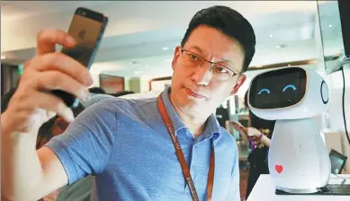  ?? KIM KYUNG-HOON / REUTERS ?? A visitor takes a selfie with Baidu’s robot Xiaodu at the 2015 Baidu World Conference in Beijing.