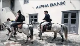  ?? PHOTO: BLOOMBERG ?? Tourists ride horses past an Alpha Bank branch on the island of Hydra, Greece last week. The country’s banks are running short on the collateral they need to stay alive.