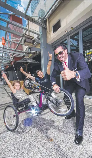  ?? Picture: NIGEL HALLETT ?? Playboy Travers ‘Candyman’ Beynon gifts Brydi Saul, who wants to be a Paralympia­n, a special $7500 bike with I Can I Will founder Conan Visser at Moo Moo.