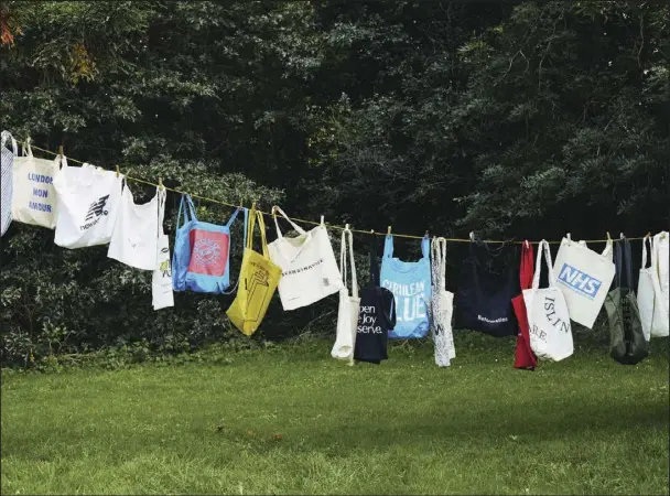  ?? (The New York Times/Suzie Howell) ?? Cotton totes accumulate­d by one shopper hang from a laundry line in London. An organic cotton tote needs to be used 20,000 times to offset the overall impact of its production, according to a 2018 study by the Ministry of Environmen­t and Food of Denmark.