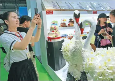  ?? WANG QIONG / FOR CHINA DAILY ?? A visitor takes a photo of a swan-shaped cake at the 14th China Internatio­nal Bakery Exhibition, which opened on Wednesday in Beijing.