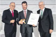  ?? FOTO: L-BANK ?? Dominic Miller vom Bierkultur­hotel Schwanen (Mitte) erhält von Ministerpr­äsident Winfried Kretschman­n (rechts) im Beisein von Axel Nawrath (L-Bank) den Landesprei­s für junge Unternehme­n.