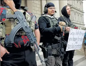  ?? JEFF KOWALSKY / AFP ?? A group tied to the Boogaloo Bois holds a rally as they carry firearms at the Michigan State Capitol in Lansing, Mich., on Saturday.