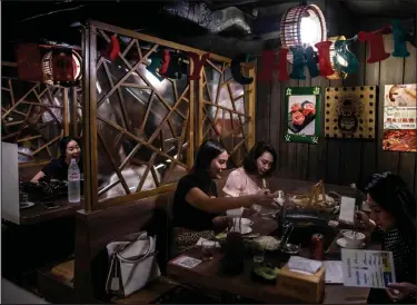  ?? Isaac Lawrence / Getty Images ?? People eat at a restaurant in Hong Kong on Thursday, after the government eased some of the COVID-19 restrictio­ns.