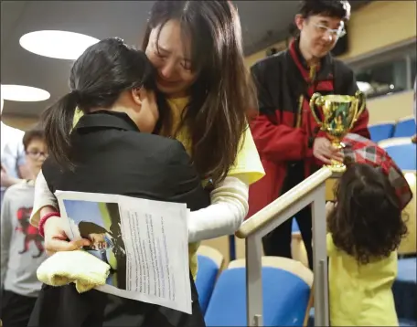  ?? PAUL CONNORS — BOSTON HERALD ?? Winship Elementary’s Tanoshi Inomata, left, is congratula­ted by his mother Hiromi,Inomata center, while his father Chikao Inomata, right, holds the winning trophy after Tanoshi won the BCYF Citywide Spelling Bee held at the Boston Public Library Saturday.