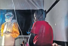  ?? [JEROME DELAY/ THE ASSOCIATED PRESS] ?? In this July 13 photo, health workers dressed in protective gear check on Ivette Adania, 24, a mother of four whose husband died of Ebola, at a treatment center in Beni, Congo.