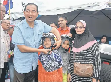  ??  ?? Ab Aziz helps Nurariana Nadia Zukkurnain put on a helmet at the Sri Gading People’s Fiesta at the Dataran Kompleks Niaga Parit Raja. — Bernama photo