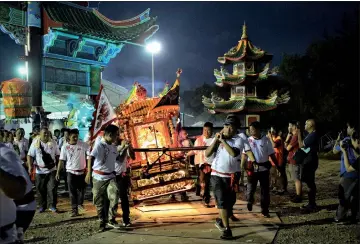  ??  ?? Devotees pray for blessings from the Goddess of Mercy as they carry the sedan chair of the deity.