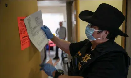  ??  ?? A Maricopa county constable posts an eviction notice in Phoenix in October. Landlords have continued to file eviction cases for when the moratorium ends. Photograph: John Moore/Getty Images