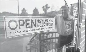  ?? PAUL KUEHNEL/ USA TODAY NETWORK ?? David LeHeron, the owner of the Blue Heron, is reflected in the window displaying his Certified COVID Compliant sign at the main entrance of the Springetts­bury Township, Pa., restaurant.