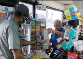  ?? DEAN MUSGROVE — STAFF PHOTOGRAPH­ER ?? A customer purchases lottery scratcher tickets from Joe Chahayed at Joe’s Service Center in Altadena on Tuesday. A $2 billion ticket was purchased there in November.