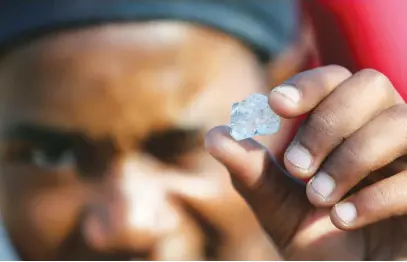  ?? Picture: Reuters ?? ALL THAT GLITTERS. A man shows a stone that has been identified as quartz crystals as fortune seekers flock to KwaHlathi outside Ladysmith, KwaZulu-Natal, after finding what they believe to be diamonds.