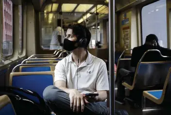  ?? ARMANDO L. SANCHEZ Chicago Tribune/TNS, file ?? David Cedras, 25, wears a mask while riding a Brown Line train in Chicago’s Loop. Many airlines and transit hubs have already lifted their mask mandates after a federal judge voided them last week.