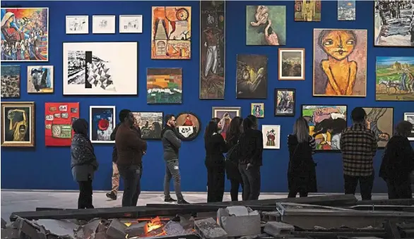  ?? — © 2024 The New York Times Company ?? Visitors looking at paintings along blue walls meant to evoke Gaza’s sky and sea at the Palestinia­n Museum in Birzeit in the West Bank.