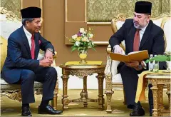  ??  ?? Royal check: Sultan Muhammad V reading the report as Mohd Sidek looks on at Istana Negara. — Bernama
