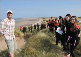  ?? Photos by Declan Malone ?? Maharees Conservati­on Associatio­n member Martha Farrell planting marram grass in Maharabeg, with shovel assistance from Jamie Knox, as part of a community effort to prevent erosion of sand dunes in the area. INSET: Cars navigating the single road to the tip of the Maharees which had to be cleared of wind-blown sand on 17 occasions during the storms of winter 2015 - 2016. RIGHT: Dr Eugene Farrell explaining the forces of erosion to Meanscoil Nua an Leith Triúigh students on the rim of a collapsed sand dune in Maharbeg. BELOW, LEFT: Local farmers Patrick Browne and Tom Scanlon who were helping with the marram grass transplant­ing project last Thursday. BELOW, RIGHT: An Taisce coastal officer Susan Vickers shows Ellen Goodwin how to transplant marram grass.