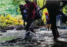  ?? ?? Migrants cross the Río Muerto on Nov. 6 as they enter the Darién Gap jungle. Numerous travelers do not make it out.