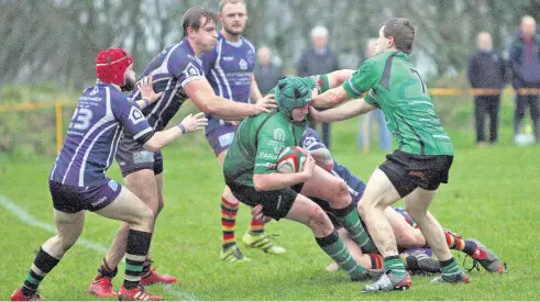  ??  ?? Bangor’s Gruff Tudor (green) in the middle of the action against Menai Bridge. Picture: RICHARD BIRCH