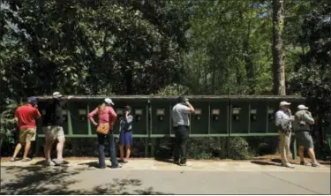  ?? CHARLIE RIEDEL — THE ASSOCIATED PRESS ?? Patrons use pay phones on the Augusta National golf course during the third round of the Masters golf tournament Saturday in Augusta, Ga. No cell phones are allowed on the course.