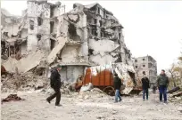  ??  ?? Syrians walk along a destroyed street in the old city of Aleppo on Saturday as pro-regime forces reopen roads that were barricaded to divide opposition and regimeheld areas. (AFP)