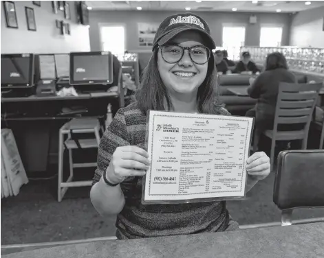  ?? TERRENCE MCEACHERN/THE GUARDIAN ?? Gabrielle Richard of Maid Marian’s Diner holds one of the English-to-Spanish translated menus on Thursday.