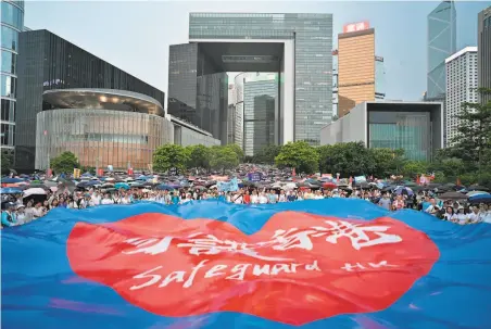  ?? Anthony Wallace / AFP / Getty Images ?? Progovernm­ent demonstrat­ors wave a banner that reads “safeguard Hong Kong” during a rally in support of Hong Kong police.